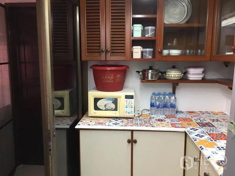 联排别墅 出租在Khlong Toei, Bangkok - 紧凑厨房，木质橱柜、彩色马赛克台面和微波炉。