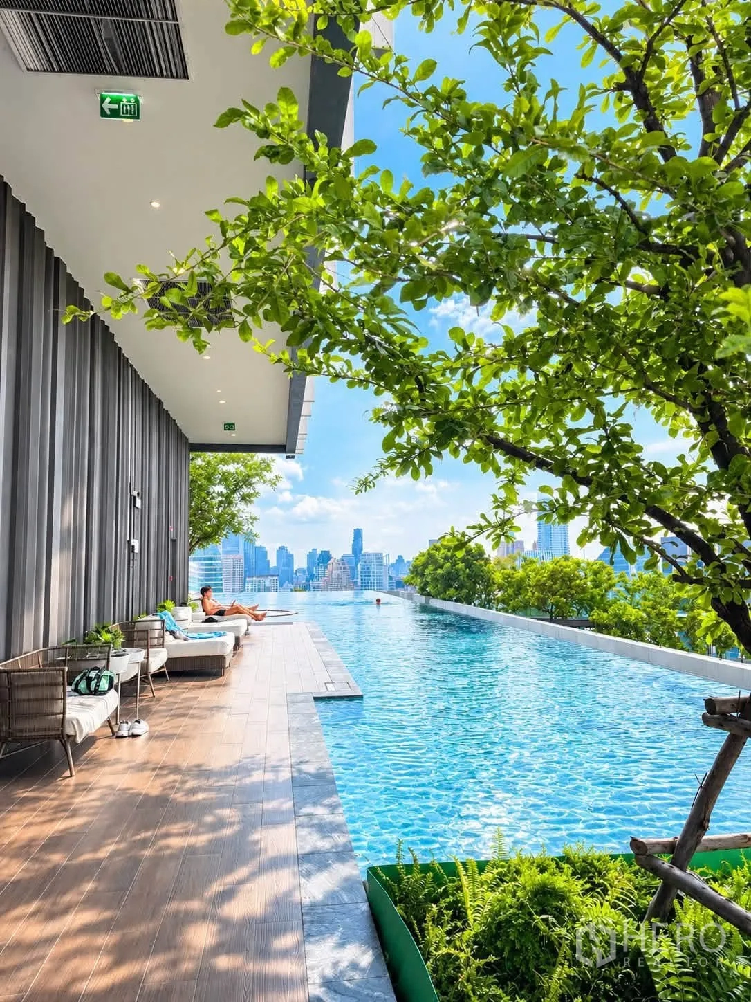 Condominium for rent in Pathum Wan, Bangkok - Pool deck with lounge chairs, greenery, and city views beside the infinity edge.
