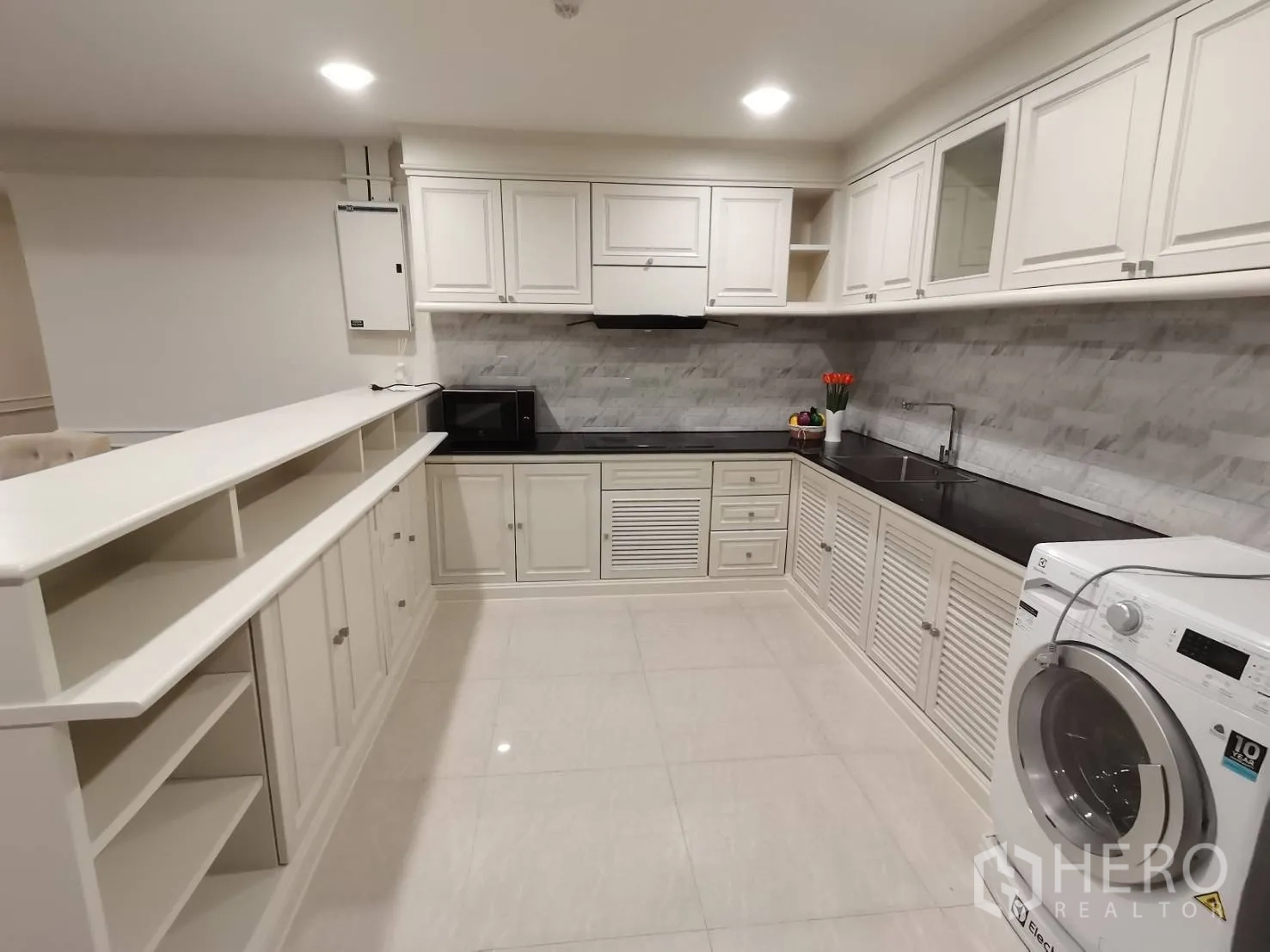 公寓 for rent in Watthana, Bangkok - 宽敞厨房，白色橱柜、黑色台面、墙面瓷砖挡板与洗衣机。