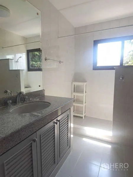 Townhouse for rent in Khlong Toei, Bangkok - Bright bathroom with granite vanity and a windowed shower area.