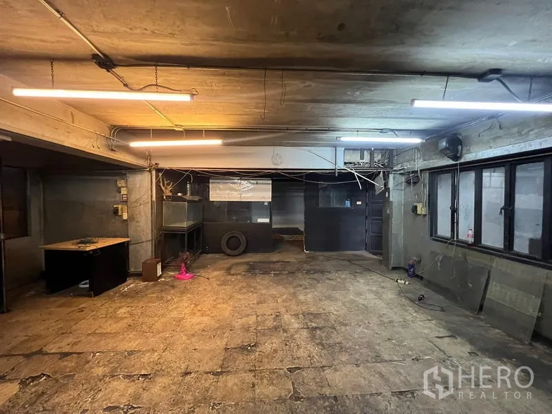 店屋 出租在Phra Khanong, Bangkok - 地下空间另一视角，带窗户和办公室隔断。
