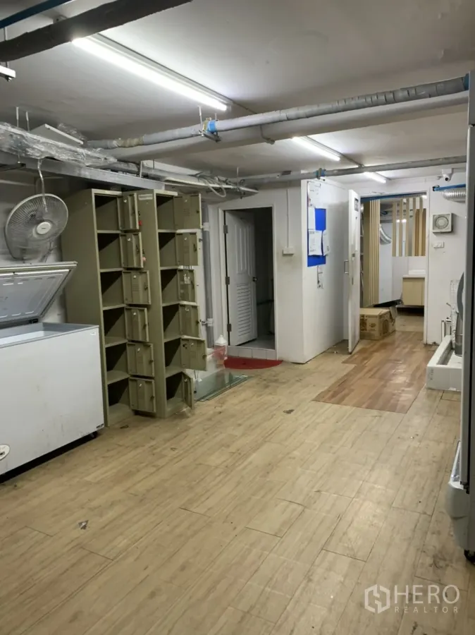 Retail Space for rent in Sathon, Bangkok - Back-of-house storage room with lockers, chest freezer and exposed ceiling pipes in a Sathon retail unit.