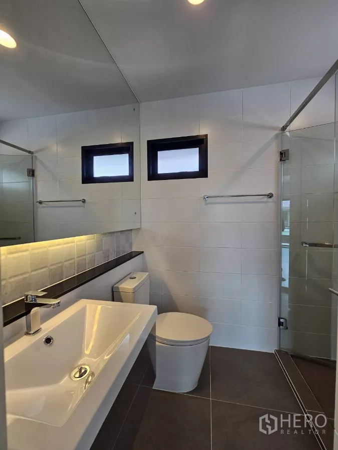 Detached House for sale in Lam Luk Ka, Pathum Thani - Modern bathroom with glass shower, large mirror and vanity.