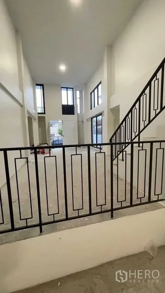 Townhouse for sale in Prawet, Bangkok - Mezzanine view over the living area with tall windows beside the stair railing.
