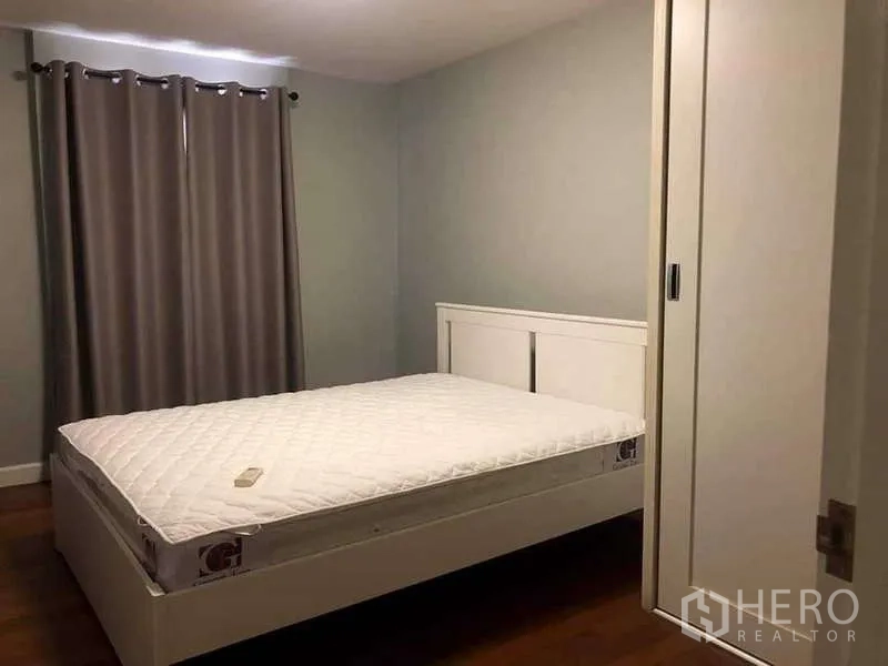 Condominium for sale in Yan Nawa, Bangkok - Guest bedroom with white bed, sliding wardrobe and dark wood floor.