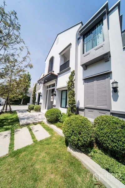 Detached House for rent in Saphan Sung, Bangkok - Two-storey house facade with manicured lawn, shrubs and classic windows.