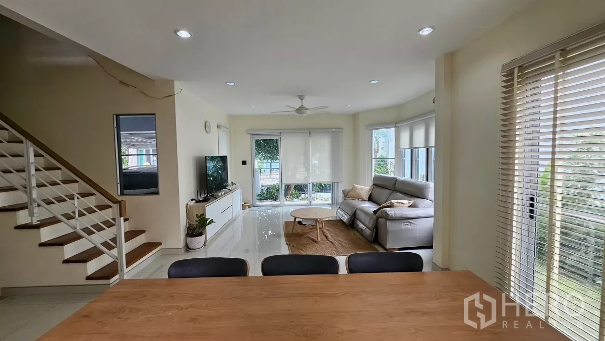 Detached House for rent in Khlong Toei, Bangkok - View from dining to lounge showing staircase, roller blinds, and sliding doors to the garden.