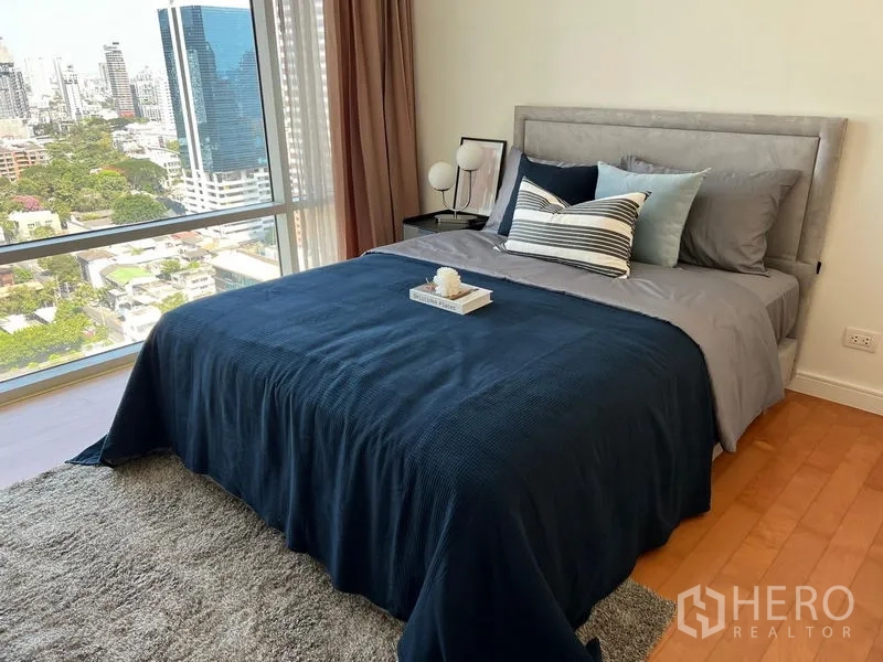 Condominium for rent in Watthana, Bangkok - Second bedroom with a large window, city view, and navy bedding on a queen-size bed.