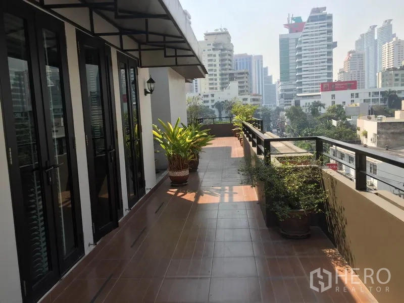 公寓 出租在Khlong Toei, Bangkok - 宽敞的私家露台，摆放盆栽，可眺望城市天际线。
