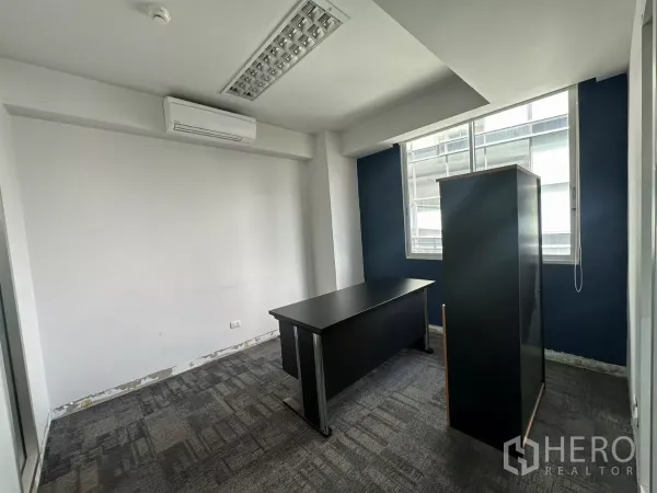 办公空间 出租在Watthana, Bangkok - 带窗户与空调的独立办公室，配深色书桌，可见轻微翻新细节。