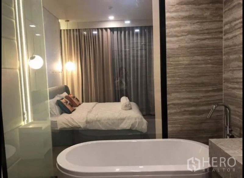 公寓 出租在Watthana, Bangkok - 套卫带独立浴缸，通过玻璃隔断与卧室相连，灯光温馨。
