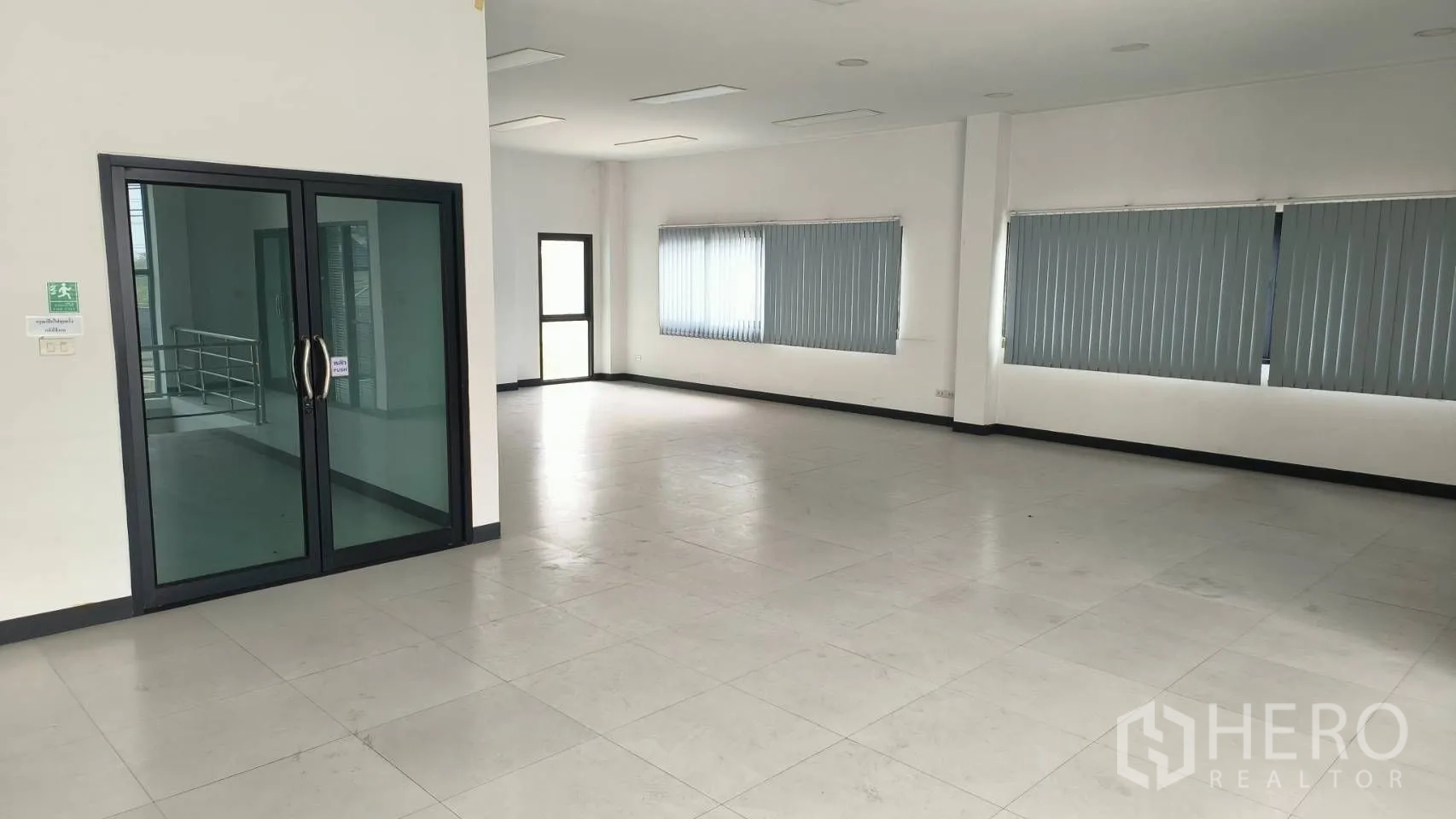 办公空间 出租在Khlong Toei, Bangkok - 明亮的楼层办公室，百叶窗与通往楼梯间的玻璃门。