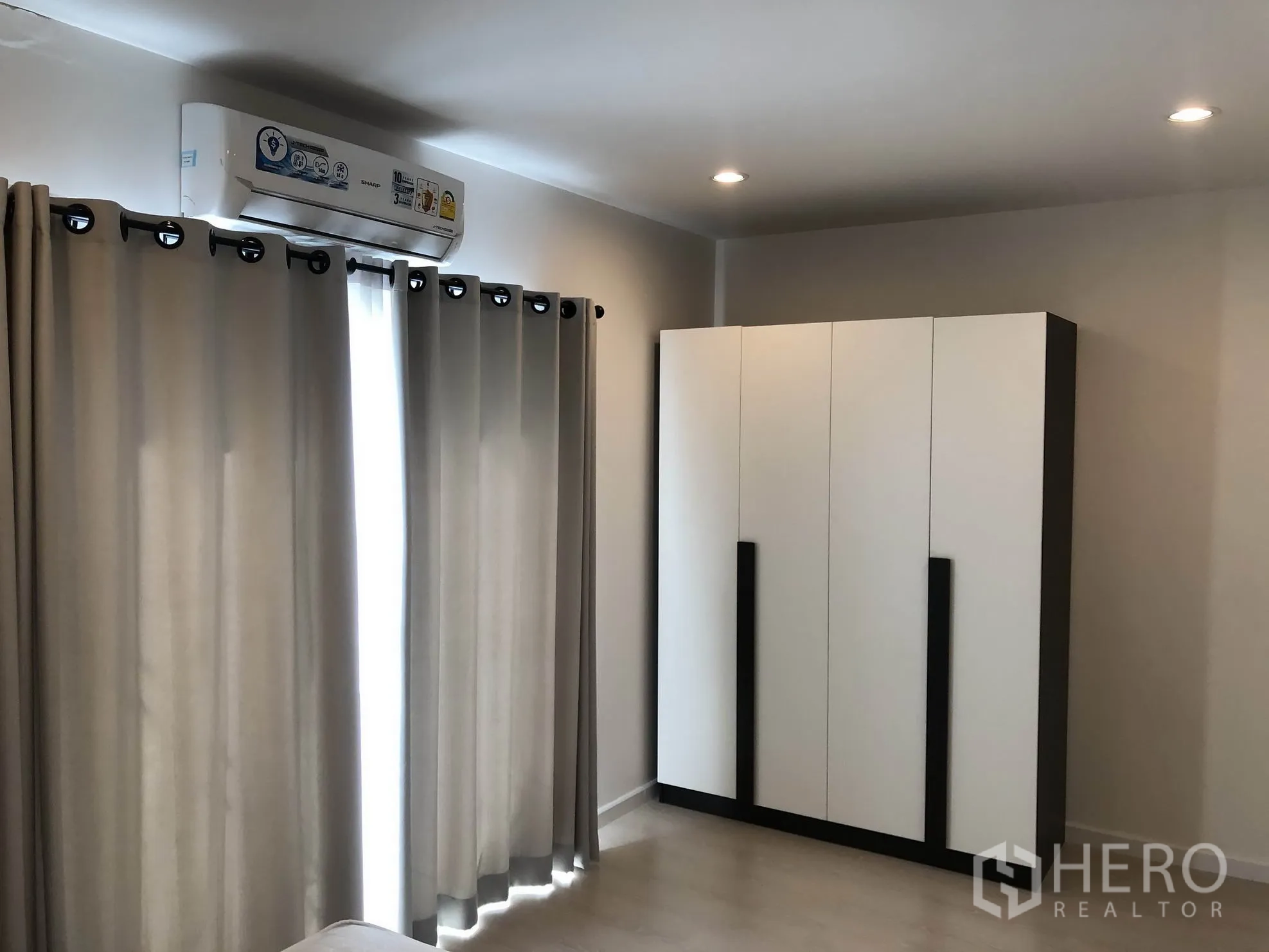 联排别墅 出租在Bang Kapi, Bangkok - 卧室一角，立式衣柜、窗帘与壁挂空调，带筒灯照明。
