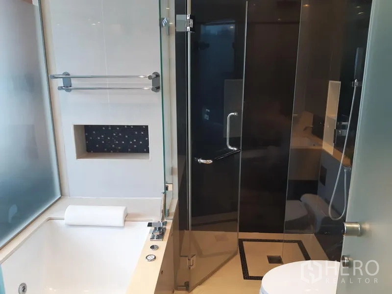 Condominium for rent in Khlong Toei, Bangkok - Bathroom featuring a soaking bathtub and separate glass shower enclosure.
