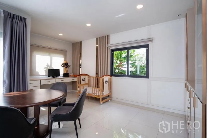 บ้าน ให้เช่าในBang Phli, Samut Prakan - โถงอเนกประสงค์ โต๊ะกลม โต๊ะทำงาน และเตียงเด็ก ข้างหน้าต่าง