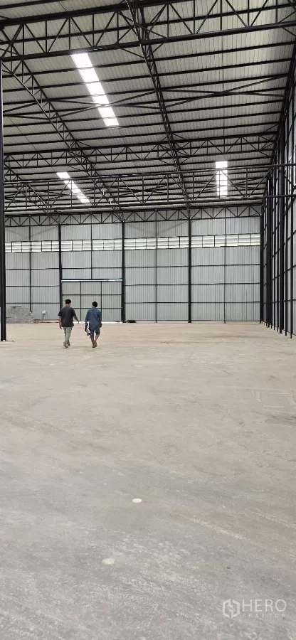 Factory for rent in Mueang Samut Sakhon, Samut Sakhon - Deep view across the open factory hall toward large access doors, showing expansive floor space.