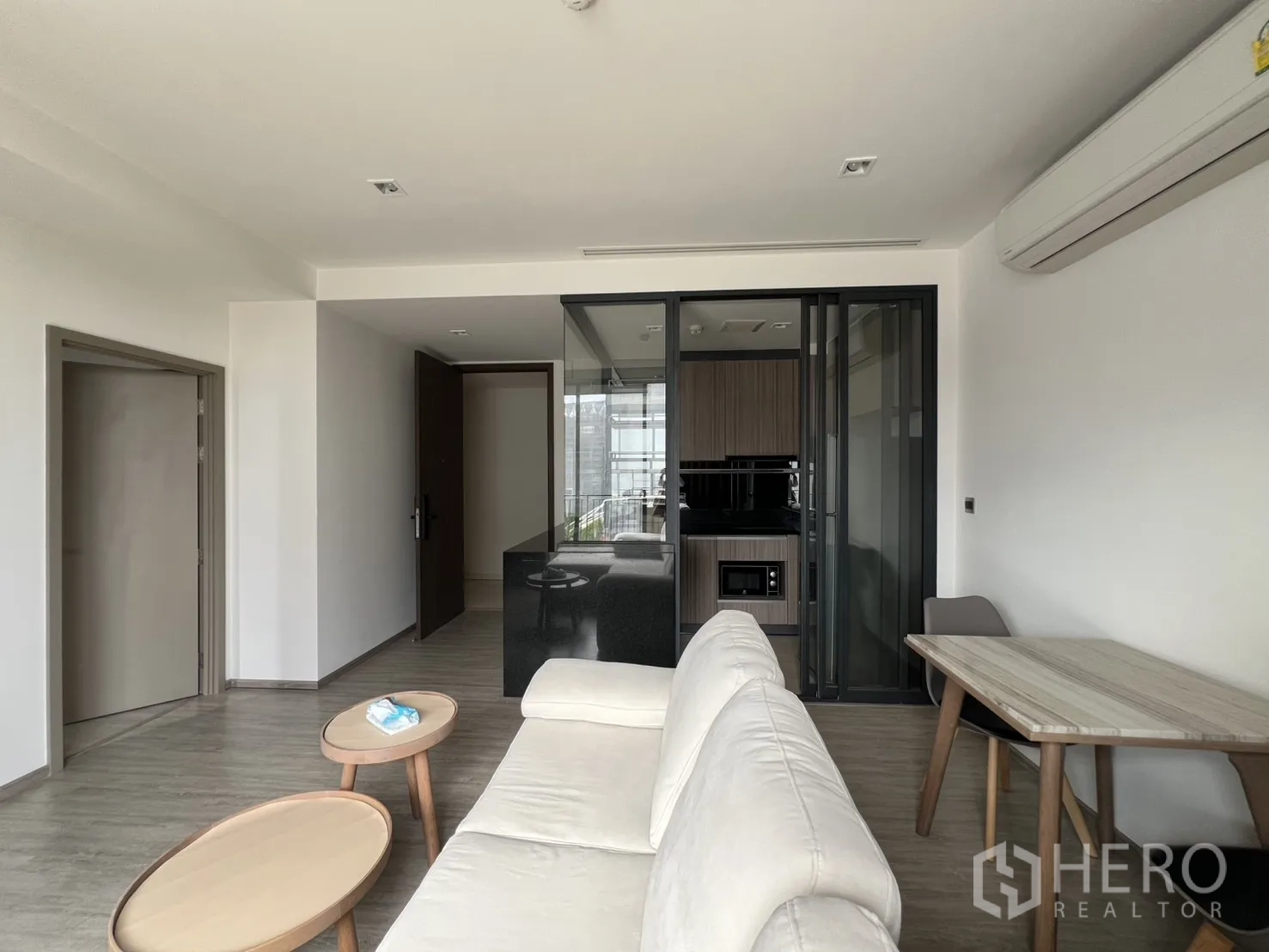 คอนโด for rent in Watthana, Bangkok - พื้นที่นั่งเล่นพร้อมโซฟา โต๊ะกลาง โต๊ะกินข้าว และครัวหลังประตูกระจกบานเลื่อน.