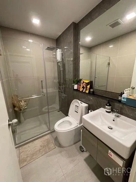 Condominium for sale - Second bathroom featuring glass shower enclosure, toilet and under-sink cabinet.