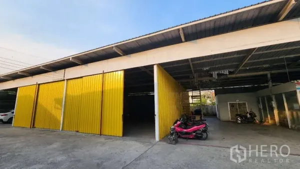 คลังสินค้า ให้เช่าในBang Khen, Bangkok - หลังคาคลุมพื้นที่ขนถ่ายสินค้าพร้อมประตูสีเหลืองเปิดกว้างและที่จอดรถหน้าโกดัง