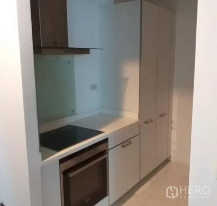 Condominium for rent in Pathum Wan, Bangkok - Cooking zone with electric cooktop, oven, and tall pantry cabinets.