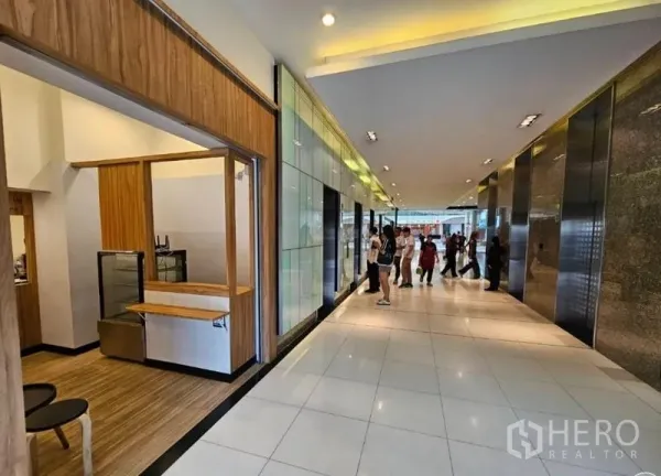 Retail Space for rent in Watthana, Bangkok - Lobby corridor with tiled floors and multiple elevators next to a shopfront and service counter.