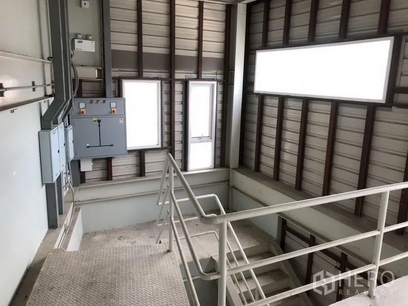 Home Office for rent in Bang Khen, Nonthaburi - Upper stairwell with metal handrails, windows and electrical control panels.