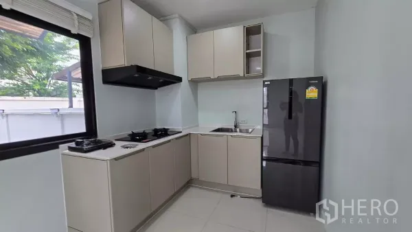 Townhouse for rent or sale in Saphan Sung, Bangkok - Close-up of L-shaped kitchen with gas hobs, range hood and upper cabinets.