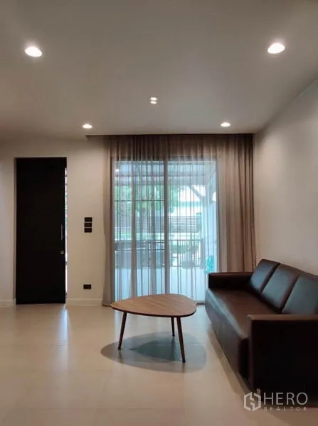 Townhouse for rent in Suan Luang, Bangkok - Bright living room with sofa, coffee table and floor-to-ceiling curtains