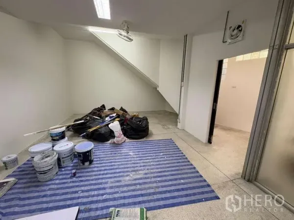 Standalone for rent in Khlong Toei, Bangkok - Ground-floor room under staircase undergoing renovation with paint cans and tools.