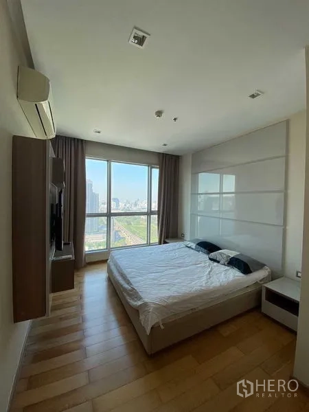 公寓 出售在Ratchathewi, Bangkok - 主卧配大床与木地板，宽窗框出城市景观。