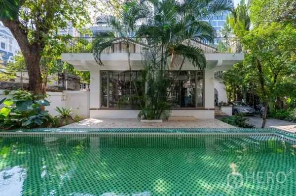 独立式住宅 出租在Pathum Wan, Bangkok - 私人绿色马赛克泳池，热带花园与现代白色外立面。