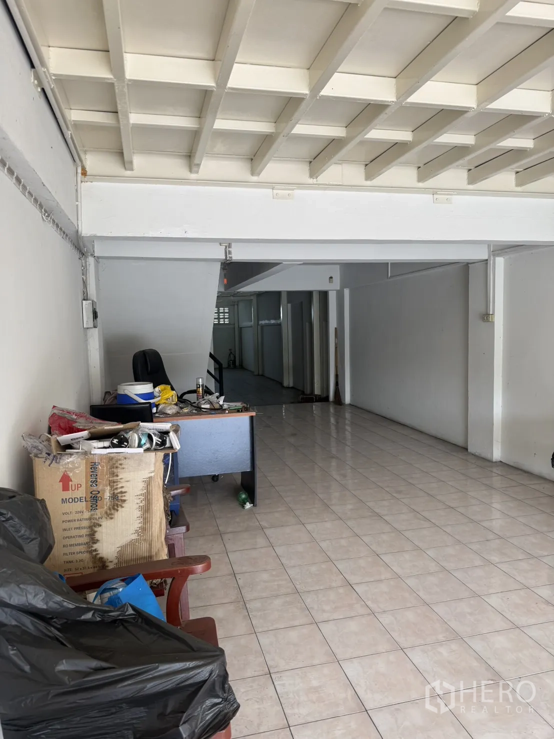Shophouse for rent in Pak Kret, Nonthaburi - Closer view of ground floor area with desk, boxes, and corridor.