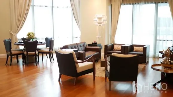 Condominium for rent in Khlong Toei, Bangkok - Spacious living and dining area with floor-to-ceiling windows, wood flooring and elegant seating.