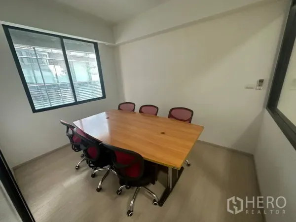 办公空间 出租在Khlong Toei, Bangkok - 小型会议室，木质会议桌与六把红色办公椅，临窗采光。