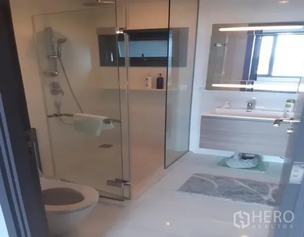 Condominium for rent in Khlong Toei, Bangkok - Contemporary bathroom featuring a glass-enclosed shower, vanity and toilet.