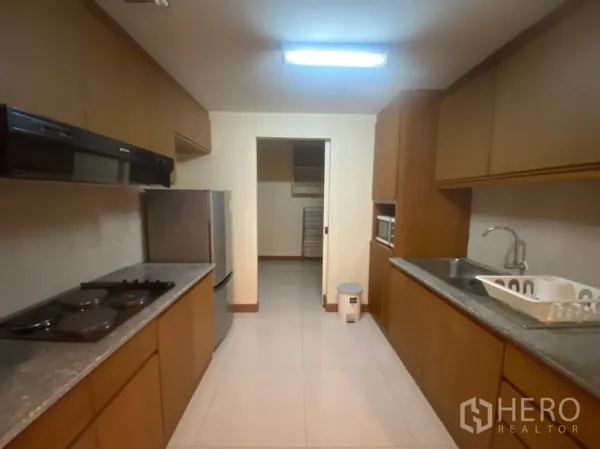 Condominium for rent in Phaya Thai, Bangkok - Separate galley kitchen with stone countertops, stovetop, hood, and full-size fridge.