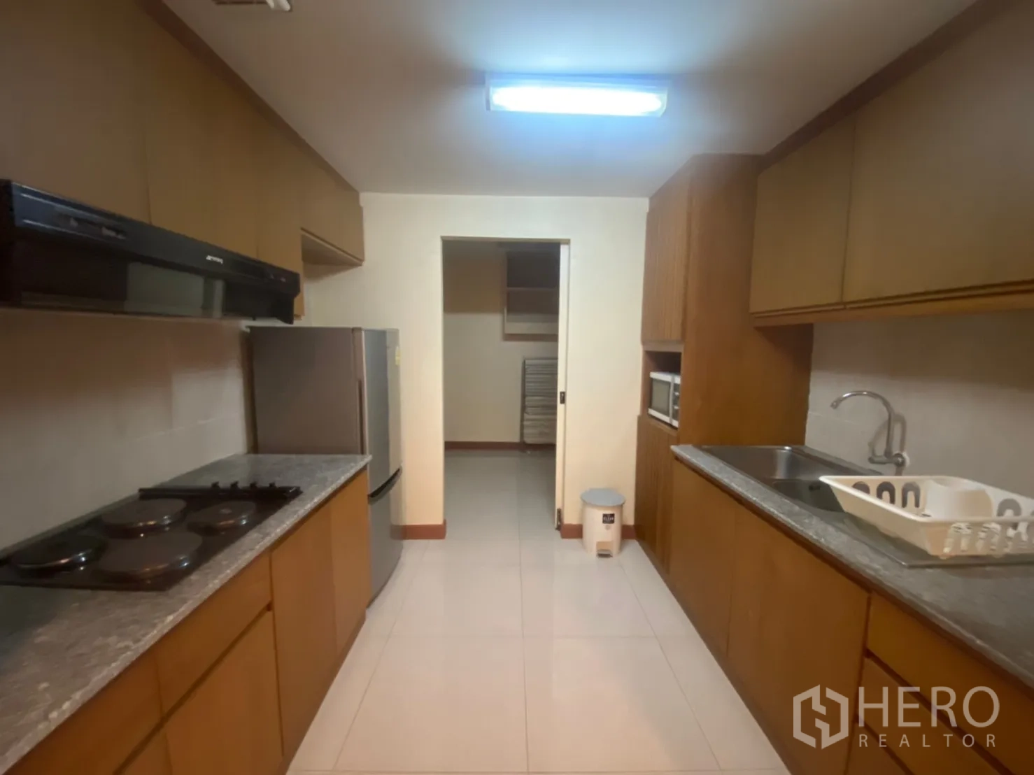 Condominium for rent in Phaya Thai, Bangkok - Separate galley kitchen with stone countertops, stovetop, hood, and full-size fridge.