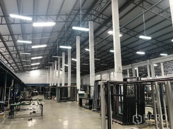 货栈 出租在Nonthaburi - 明亮工业大厅，钢桁架屋顶与悬挂灯具和作业区