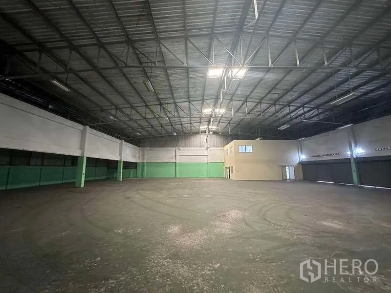 Factory for rent in Nonthaburi - Expansive warehouse floor with skylights and an internal two-storey office block.