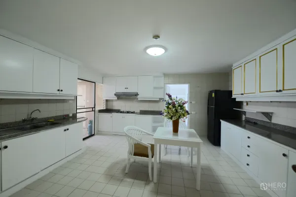 Condominium for rent or sale in Watthana, Bangkok - Large separate kitchen with white cabinetry, granite counters, gas hob, fridge and eat-in table