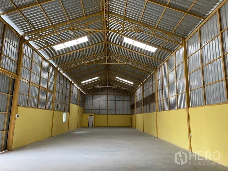 货栈 出租在Lat Krabang, Bangkok - 仓库内部空间宽阔，金属人字形高屋顶与采光板，通透混凝土地面。