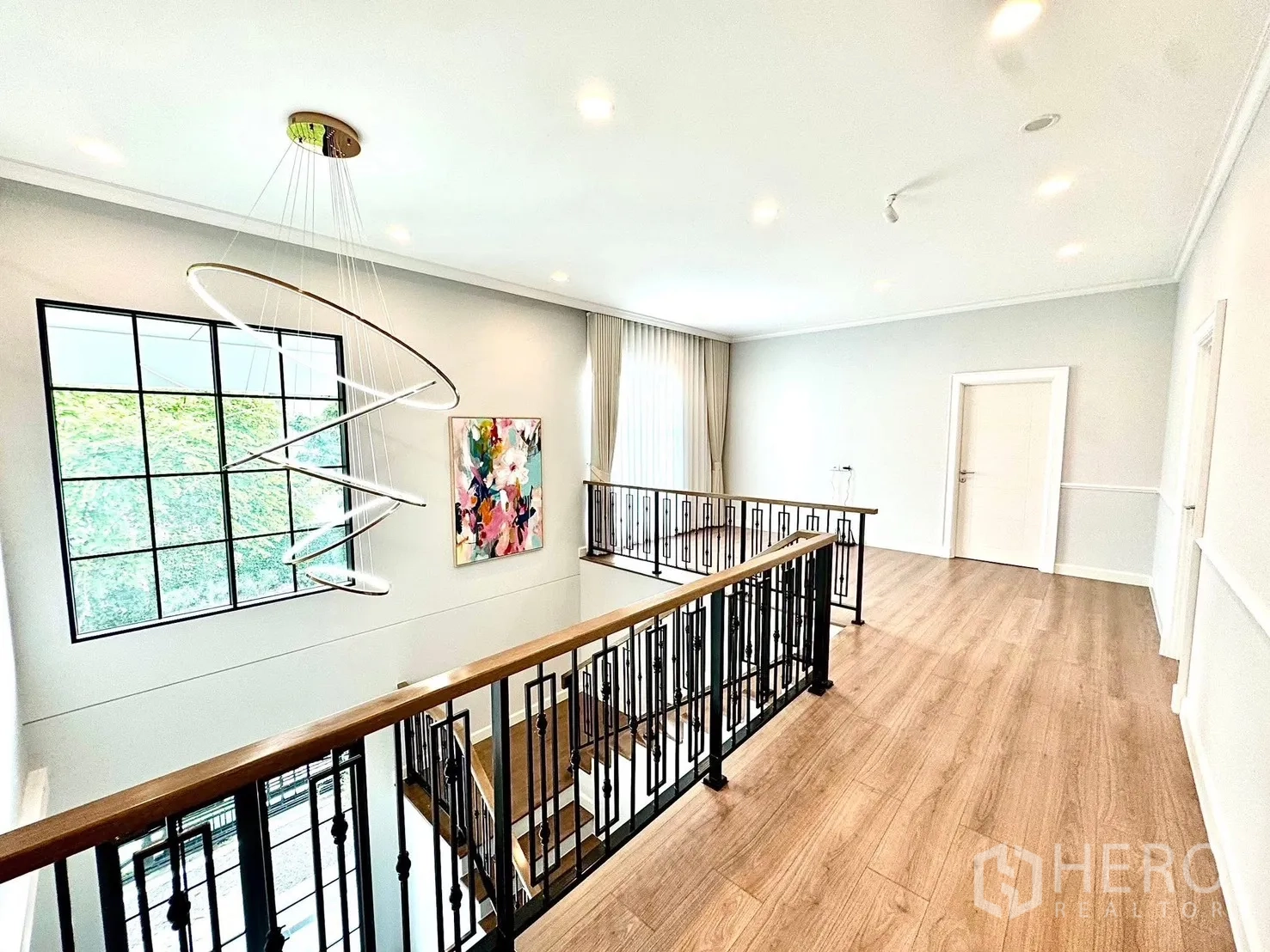 Detached House for rent in Bang Phli, Samut Prakan - Upper landing with wrought-iron railing, large window and a sculptural ring chandelier.
