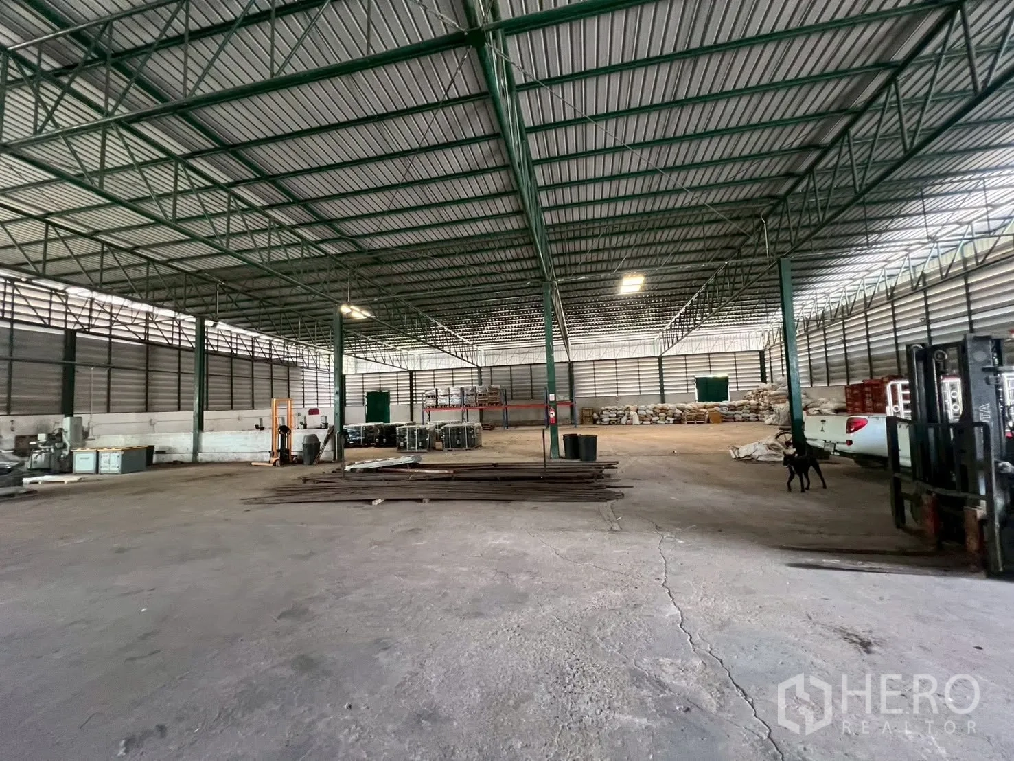 Warehouse for rent in Bang Phli, Samut Prakan - Large warehouse interior with steel truss roof, concrete floor, lighting, and open storage areas.