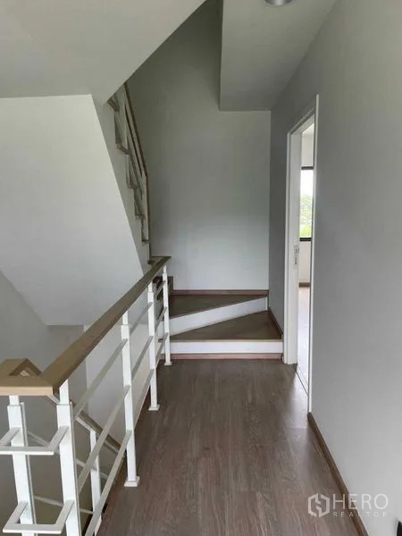 Townhouse for sale in Bueng Kum, Bangkok - Staircase and hallway with white railing connecting upper floors of the home.