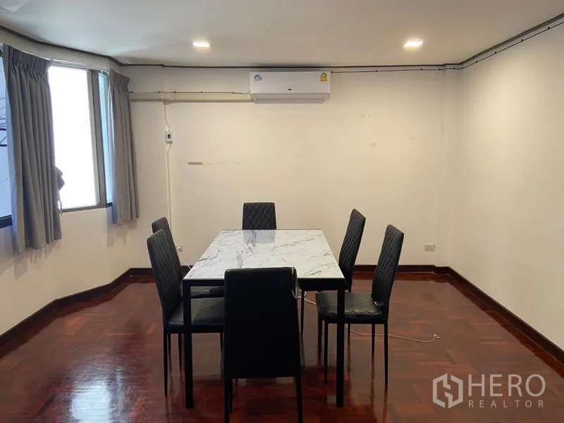 联排别墅 出租在Khlong Toei, Bangkok - 餐厅设大理石台面餐桌与六把椅子，木地板、窗户和分体空调。