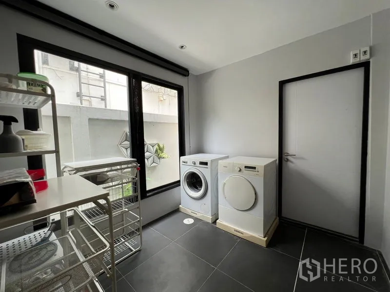 Townhouse for rent in Saphan Sung, Bangkok - Laundry room with washer, dryer, shelving, and large window.