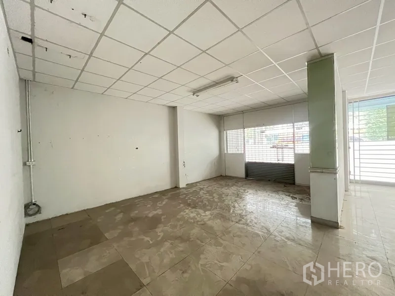 Shophouse for rent in Phra Khanong, Bangkok - Front shop space on the ground floor with roll-up shutter, tiled floor and columns.