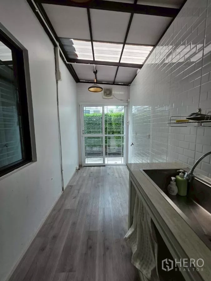 Detached House for rent or sale in Samut Prakan - Back entrance of the Thai kitchen with skylight roof and screen door to garden.