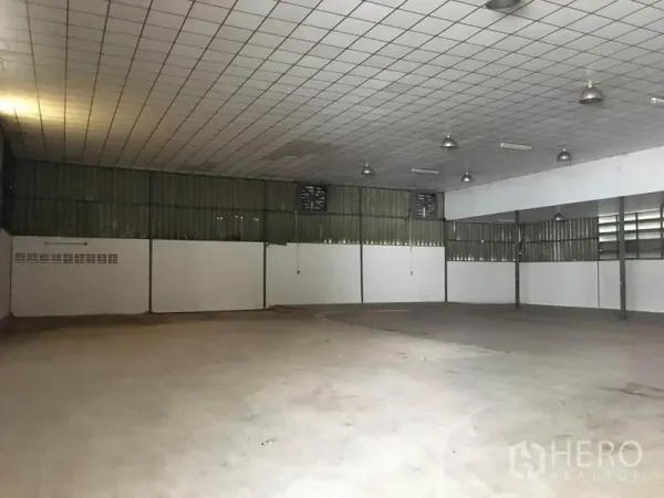 Warehouse for rent in Prawet, Bangkok - Large open storage hall with tiled acoustic ceiling, pendant lighting and ventilated side wall panels.