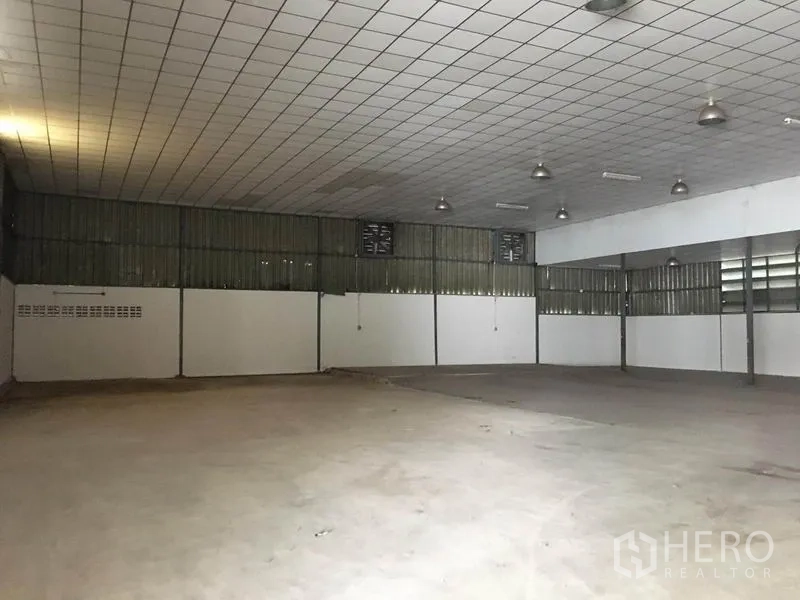 Warehouse for rent in Prawet, Bangkok - Large open storage hall with tiled acoustic ceiling, pendant lighting and ventilated side wall panels.